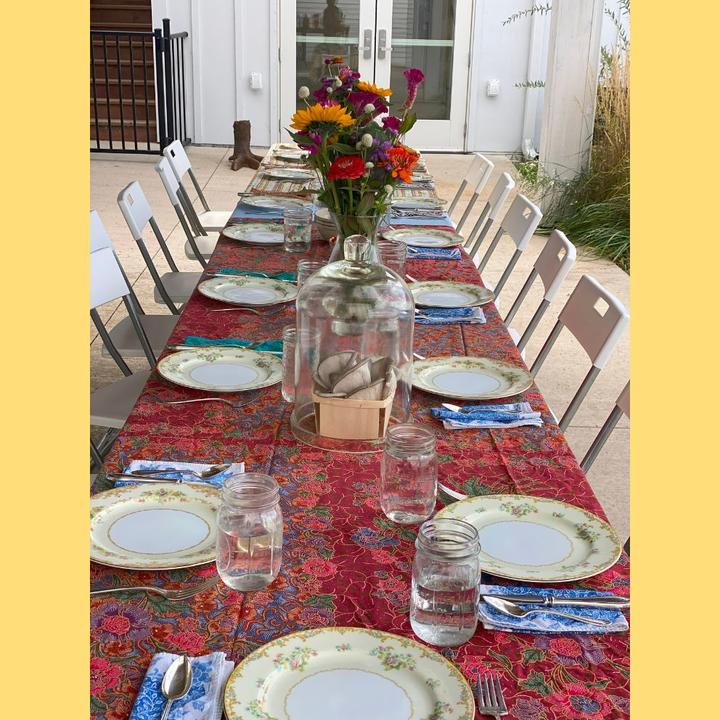 A colorful table setting with glasses, plates, napkins, and a vase of flowers